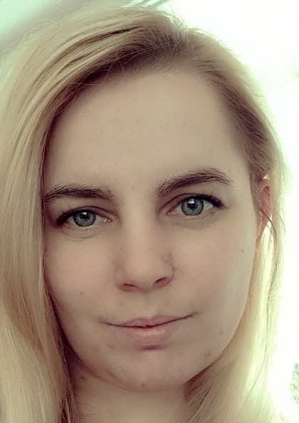 Nahaufnahme eines Porträts einer Frau mit langen blonden Haaren und blauen Augen, die direkt in die Kamera blickt.